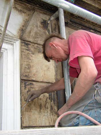 Tino beim Abspachteln der alten Fassadenfarbe